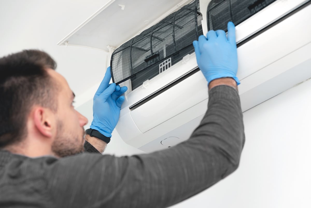 Technician repairing air conditioner appliance. Young man takes care of the cleanliness of the air-conditioning