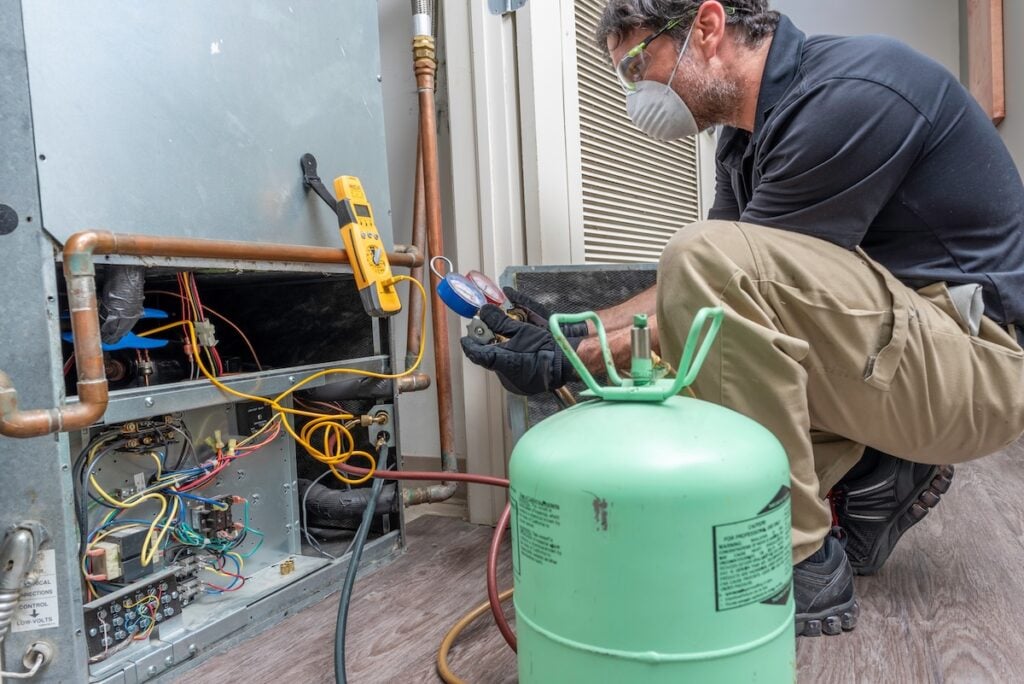 HVAC contractor wearing PPE, servicing a heat pump