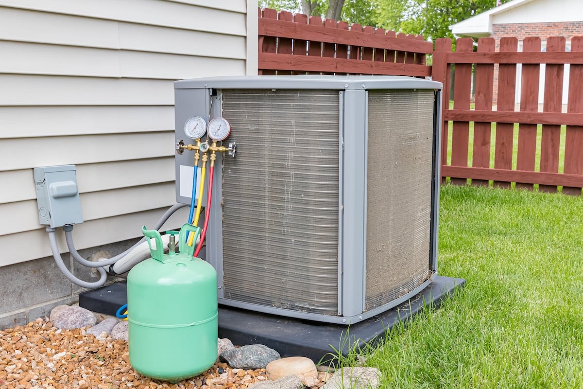 Dirty air conditioning unit. Condenser coils full of dirt and grass debris. Freon charging tools. Concept of home air conditioner repair, service, cleaning and maintenance