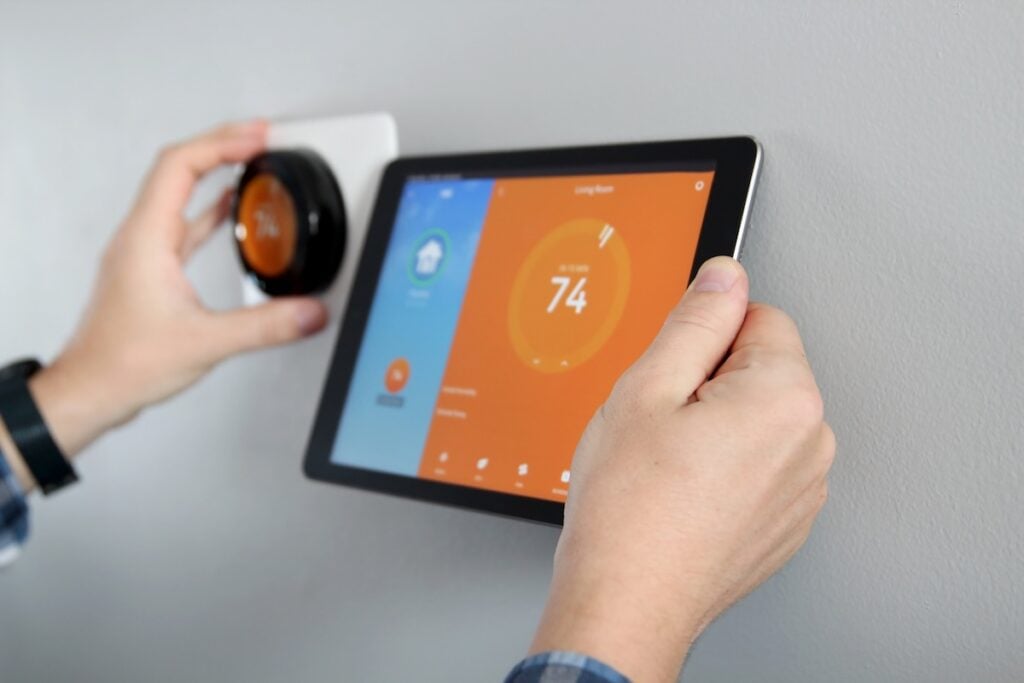 Man is Adjusting a temperature using a tablet with smart home app in modern living room best smart thermostat
