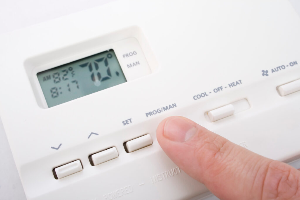 best ac temperature for energy saving Closeup shot of male hand adjusting thermostat to 70 degrees