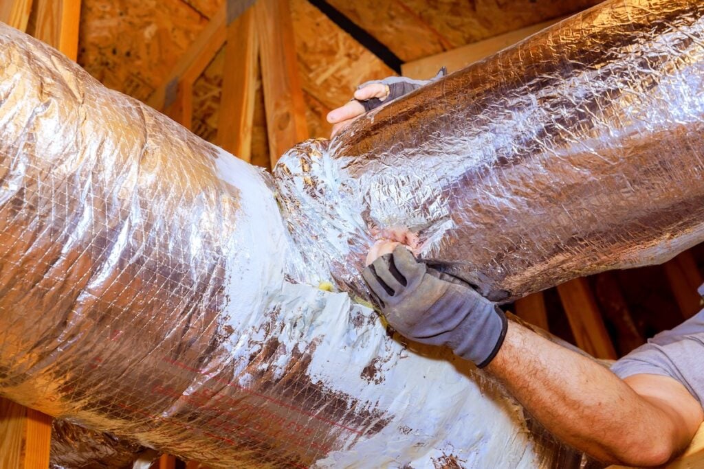 ductwork insulation Workers are sealing duct connections in attic to ensure proper airflow, energy efficiency at home.