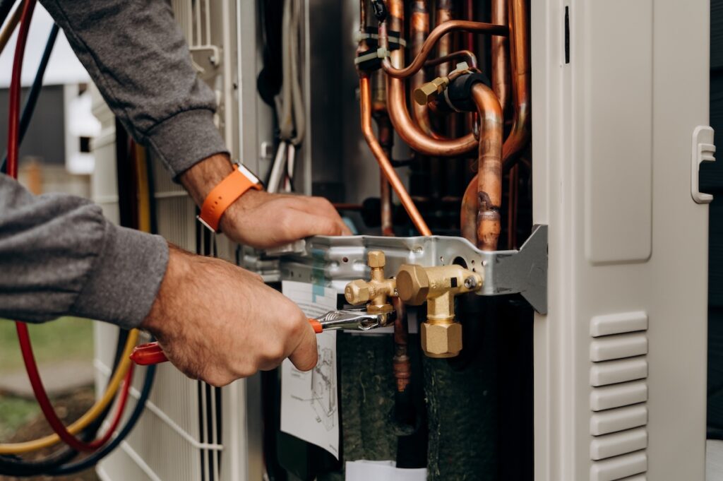 hvac tools Technician's hands with tools working on the copper pipes of the air conditioner. The photo shows parts of the cooling system and connecting valves.