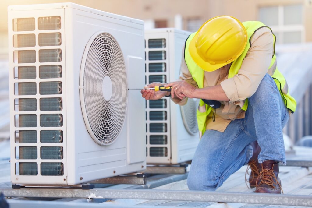 Air conditioning, technician or engineer on the roof for maintenance, building or construction of fan HVAC repair thanks to professional roof tools.