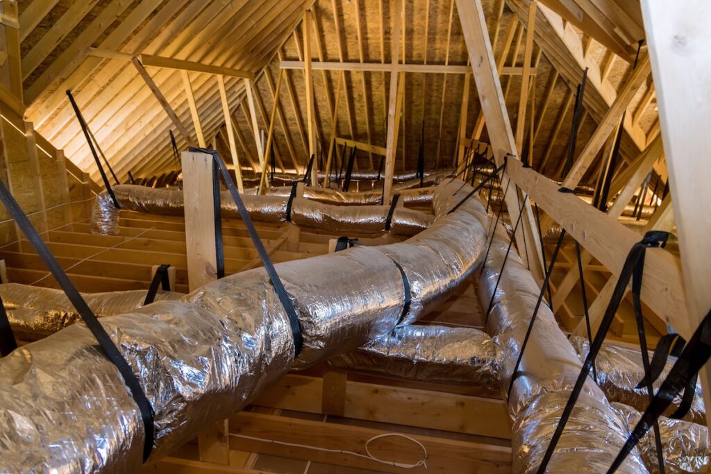 hvac duct installation In newly built home under construction ventilation pipes are silver insulation material on ceiling of attic