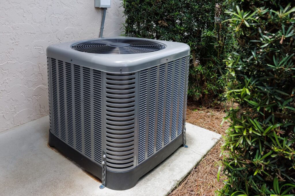how to maintain heating and air conditioning Modern HVAC air conditioner unit on concrete slab outside of house.