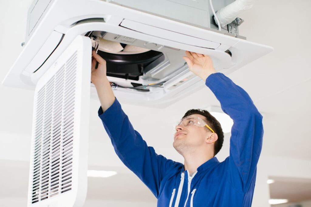 commercial hvac installation young man with blue working clothes safety glasses repairing air conditioner unit
