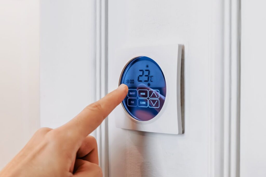 modern energy saving thermostat blue screen black numbers 23°C a hand adjusting temperature