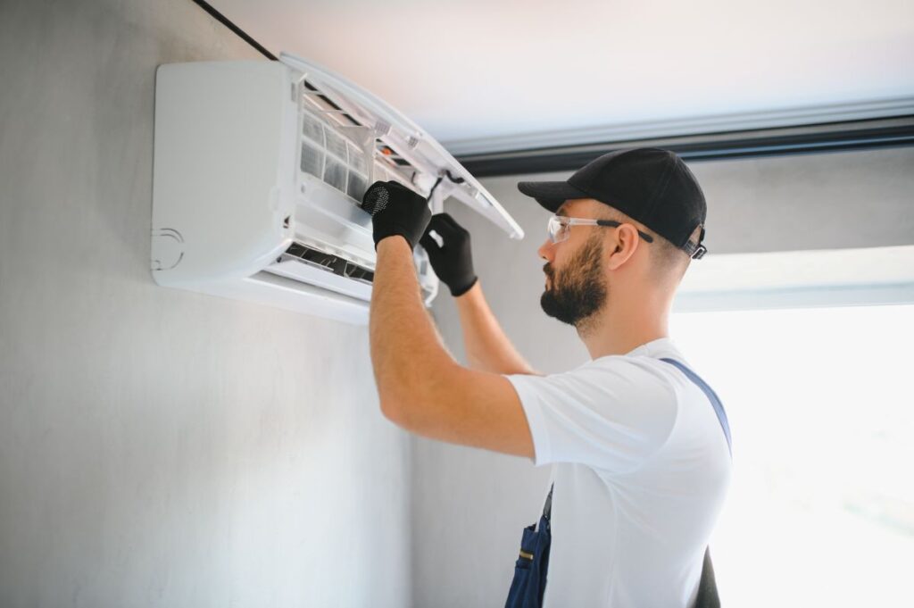 furnace cleaning male technician using white clothes and black cap repairing air conditioner