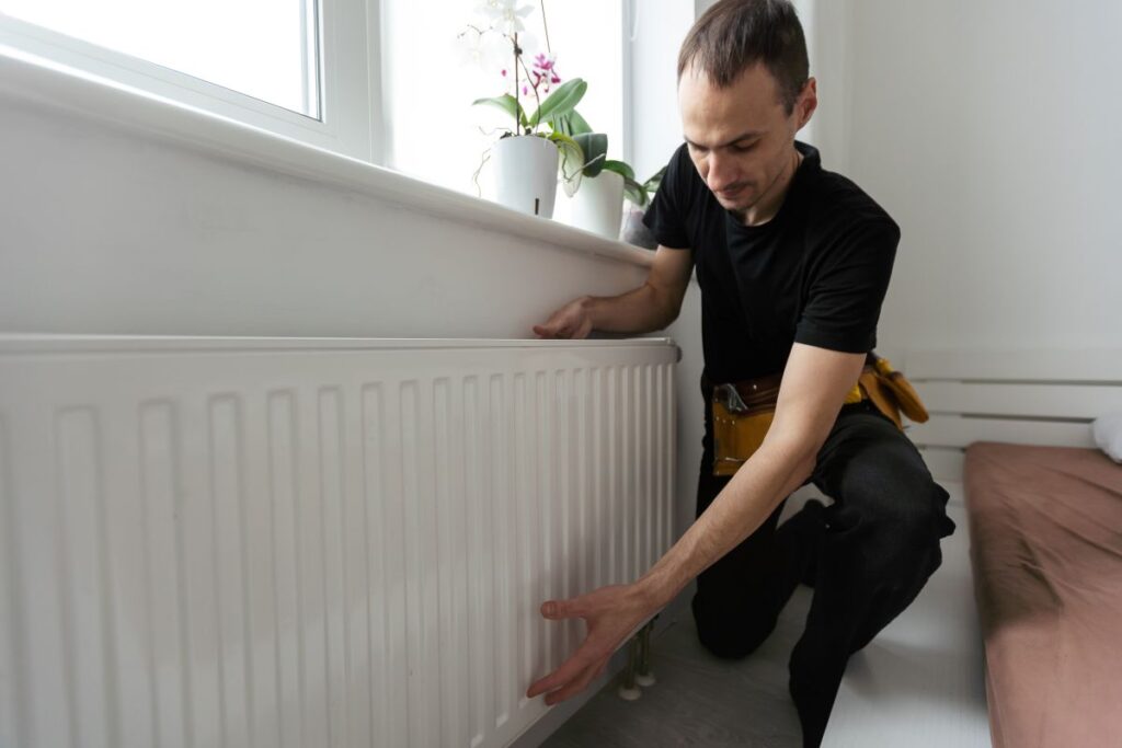 thermostat replacement worker with black clothes installing new battery inside family home