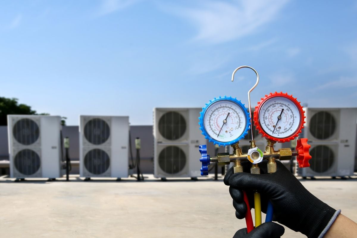 Electrical conditioning service technician using measuring manifold gauge checking HVAC