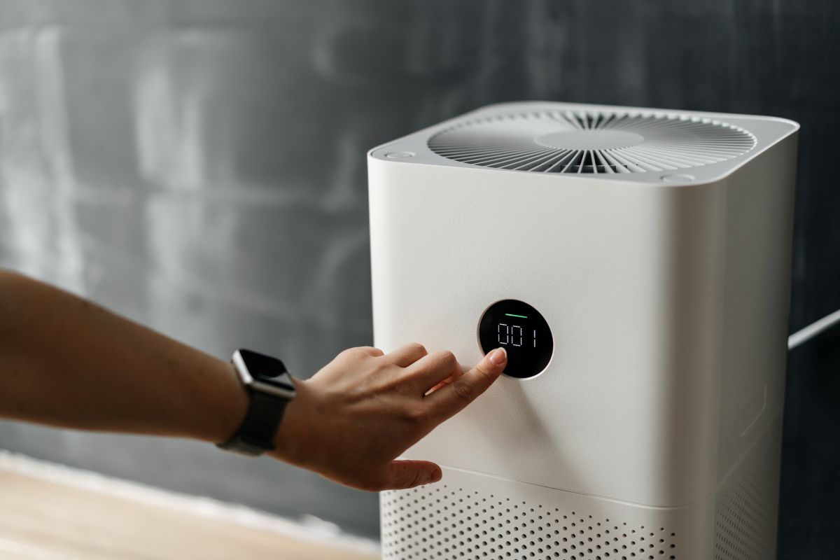 woman's hand presses the touch screen button to start an air purifier in her apartment