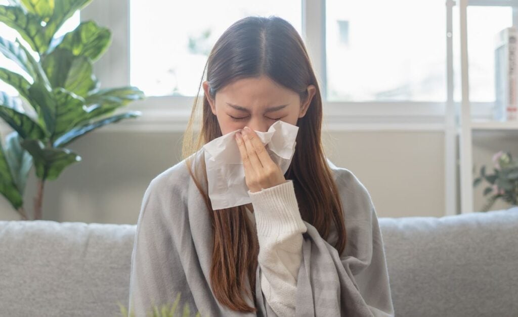 young woman is sneezing on the sofa