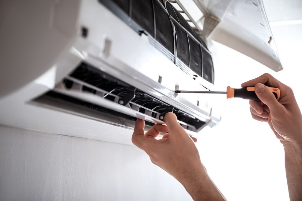 Electrician repairing air conditioner indoors
