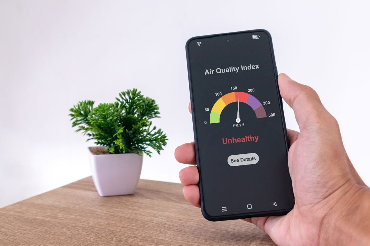Man in room checking indoor air quality index using a smartphone