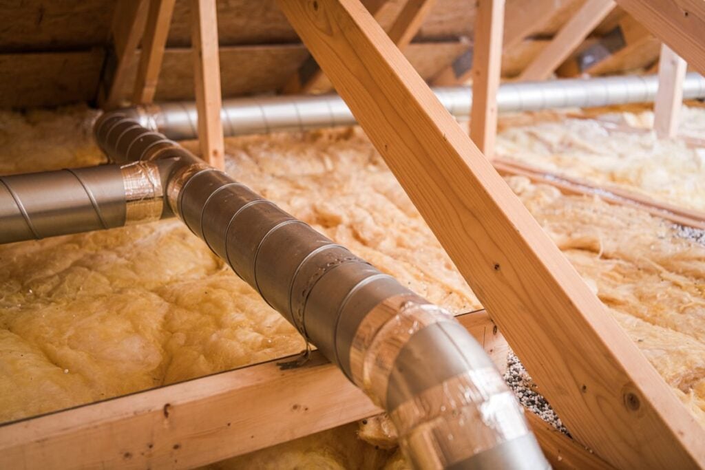 Ventilation Ducts Installed in Residential Attic With Insulation for Energy Efficiency During Winter Season
