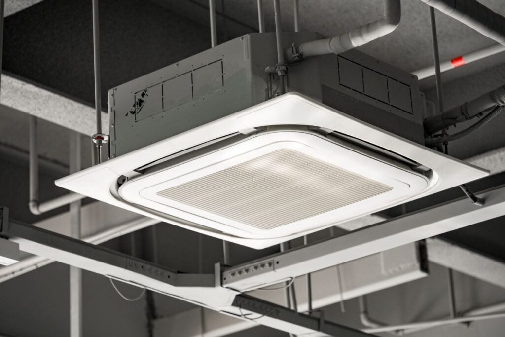 Ceiling-mounted square cassette air conditioning unit with metal grille and ventilation system