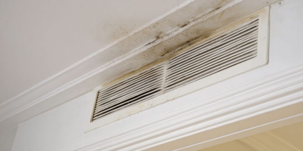 Mold and dust accumulated on ceiling air vent in room