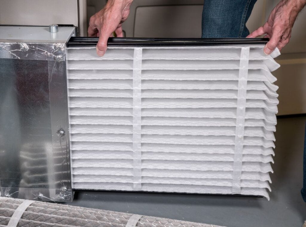 man inserting a new air filter in HVAC furnace