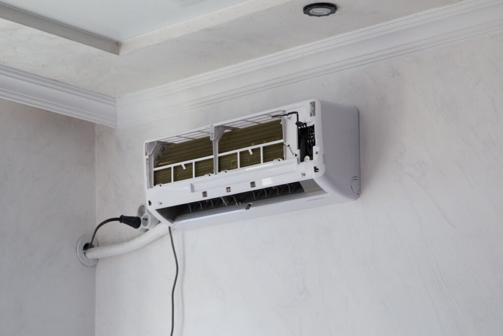 Wall-mounted air conditioner unit opened for repair and filter cleaning