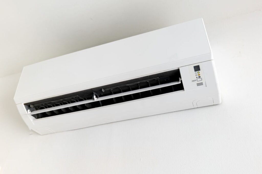 Wall-mounted split air conditioner unit on white wall, indoor climate control.